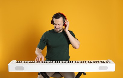 Photo of Man in headphones playing synthesizer on orange background