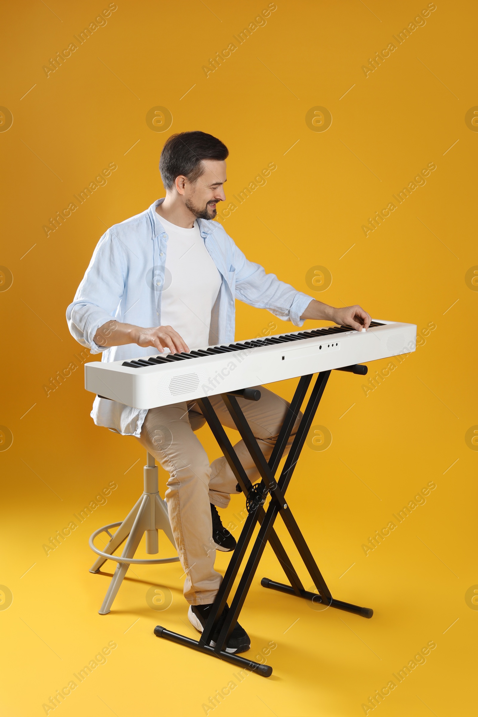 Photo of Bearded man playing synthesizer on orange background