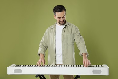 Photo of Bearded man playing synthesizer on olive background