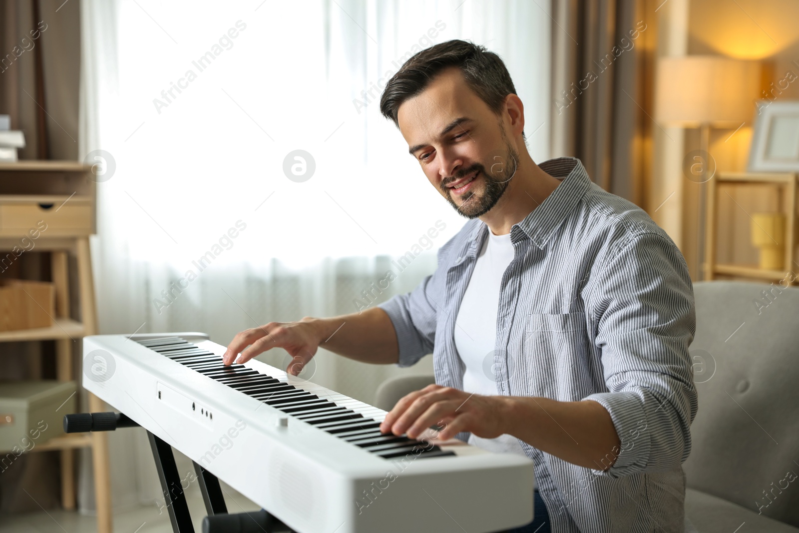 Photo of Man playing synthesizer at home. Electronic musical instrument