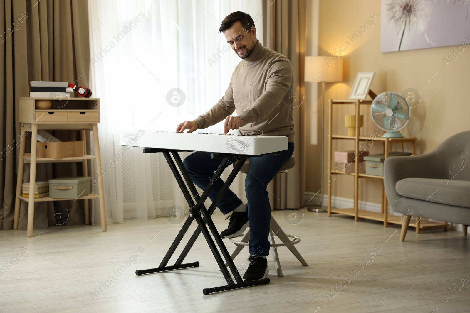 Photo of Smiling man playing synthesizer at home. Electronic musical instrument