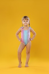 Photo of Cute little girl in swimsuit on orange background