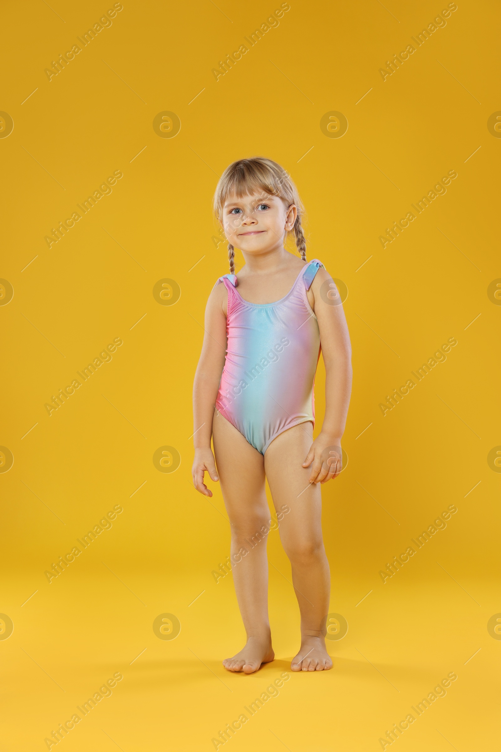 Photo of Cute little girl in swimsuit on orange background