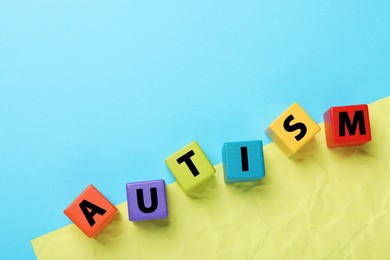 Photo of Word Autism made of colorful cubes on color background, top view. Space for text