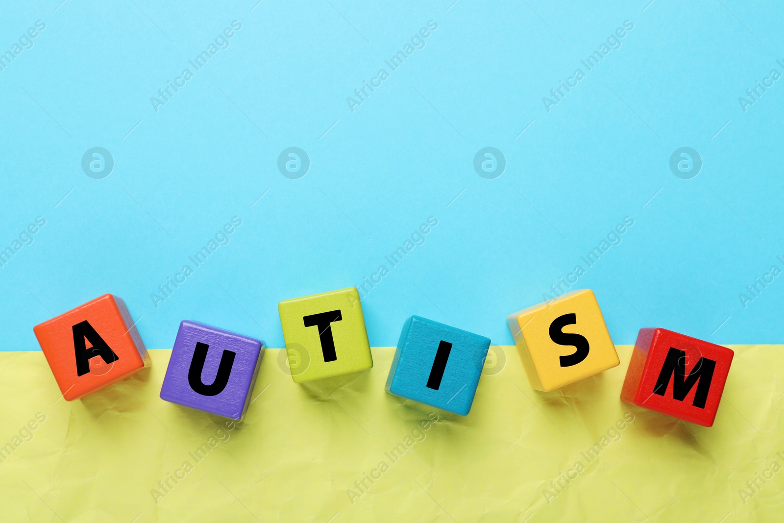 Photo of Word Autism made of colorful cubes on color background, top view. Space for text