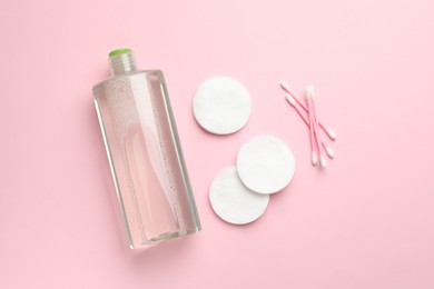 Photo of Cotton pads, swabs and bottle of cosmetic product on pink background, flat lay