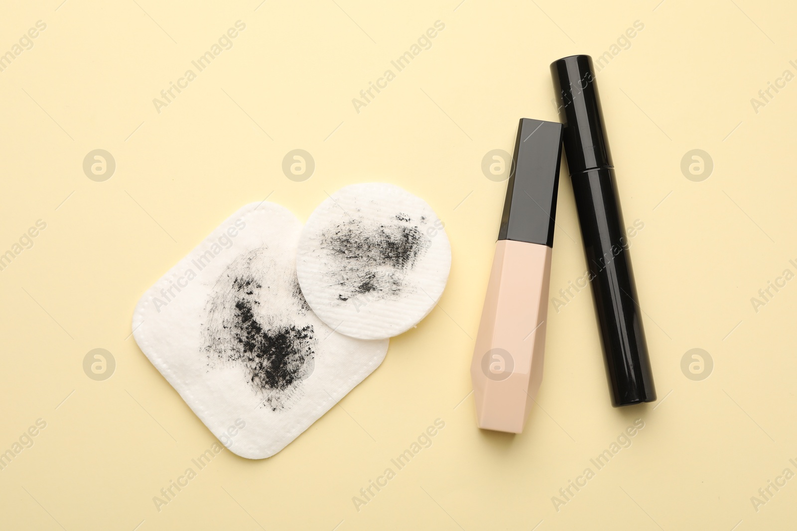 Photo of Dirty cotton pads and makeup products on beige background, flat lay