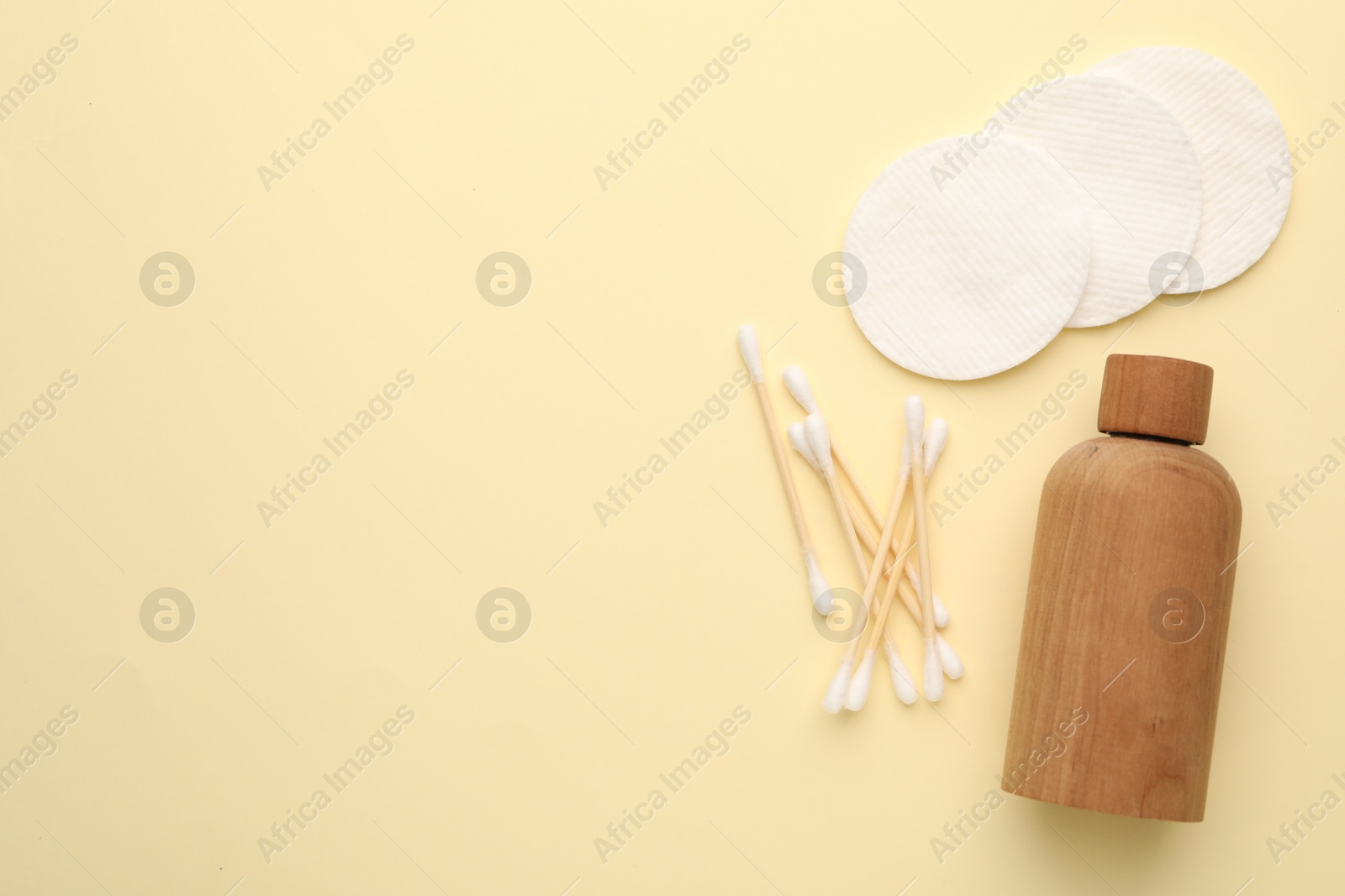 Photo of Cotton pads, bottle of cosmetic product and swabs on beige background, flat lay. Space for text