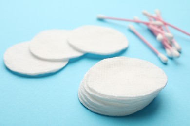 Photo of Cotton pads and swabs on light blue background, closeup