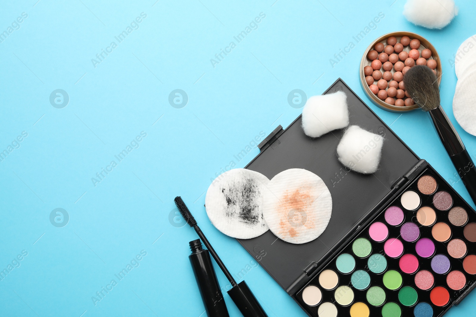 Photo of Flat lay composition with cotton pads and makeup products on light blue background, space for text