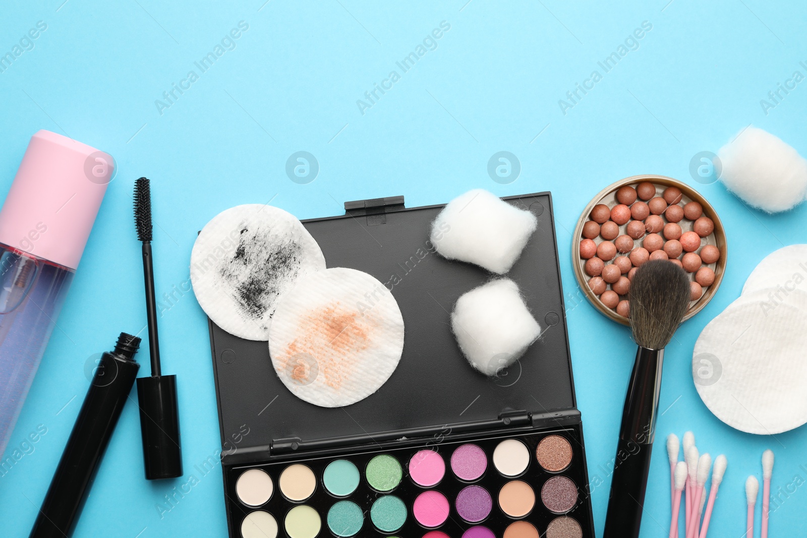 Photo of Flat lay composition with cotton pads and makeup products on light blue background