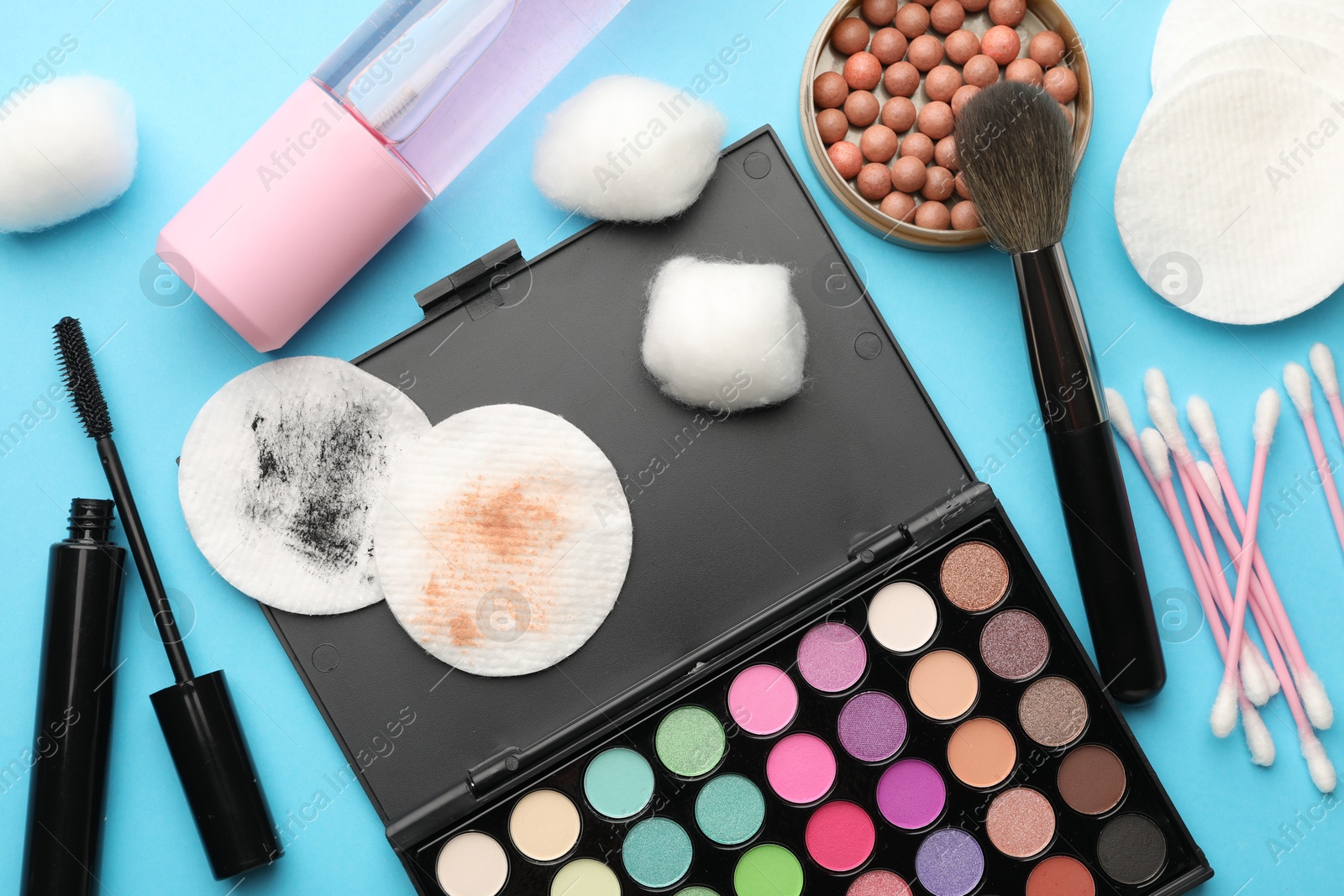 Photo of Flat lay composition with cotton pads and makeup products on light blue background