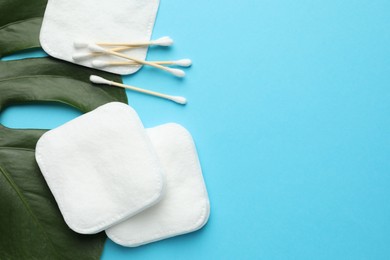 Photo of Cotton pads, swabs and monstera leaf on light blue background, flat lay. Space for text