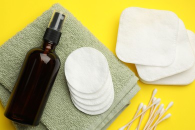 Photo of Cotton pads, cosmetic product, swabs and towel on yellow background, flat lay