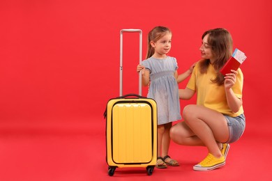 Photo of Traveller with suitcase. Young woman and cute little girl on red background, space for text