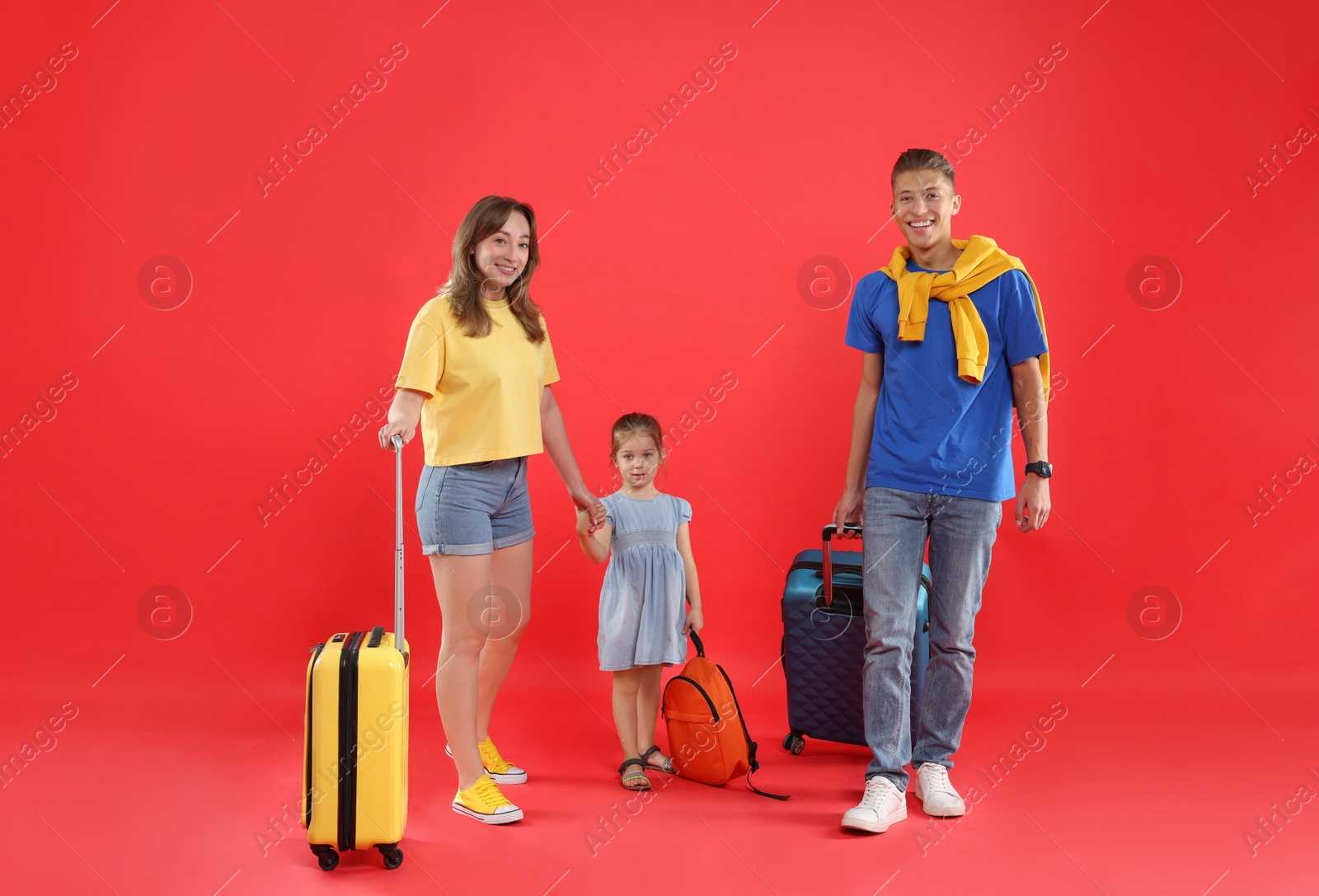 Photo of Travellers with suitcases and backpack. Happy family on red background