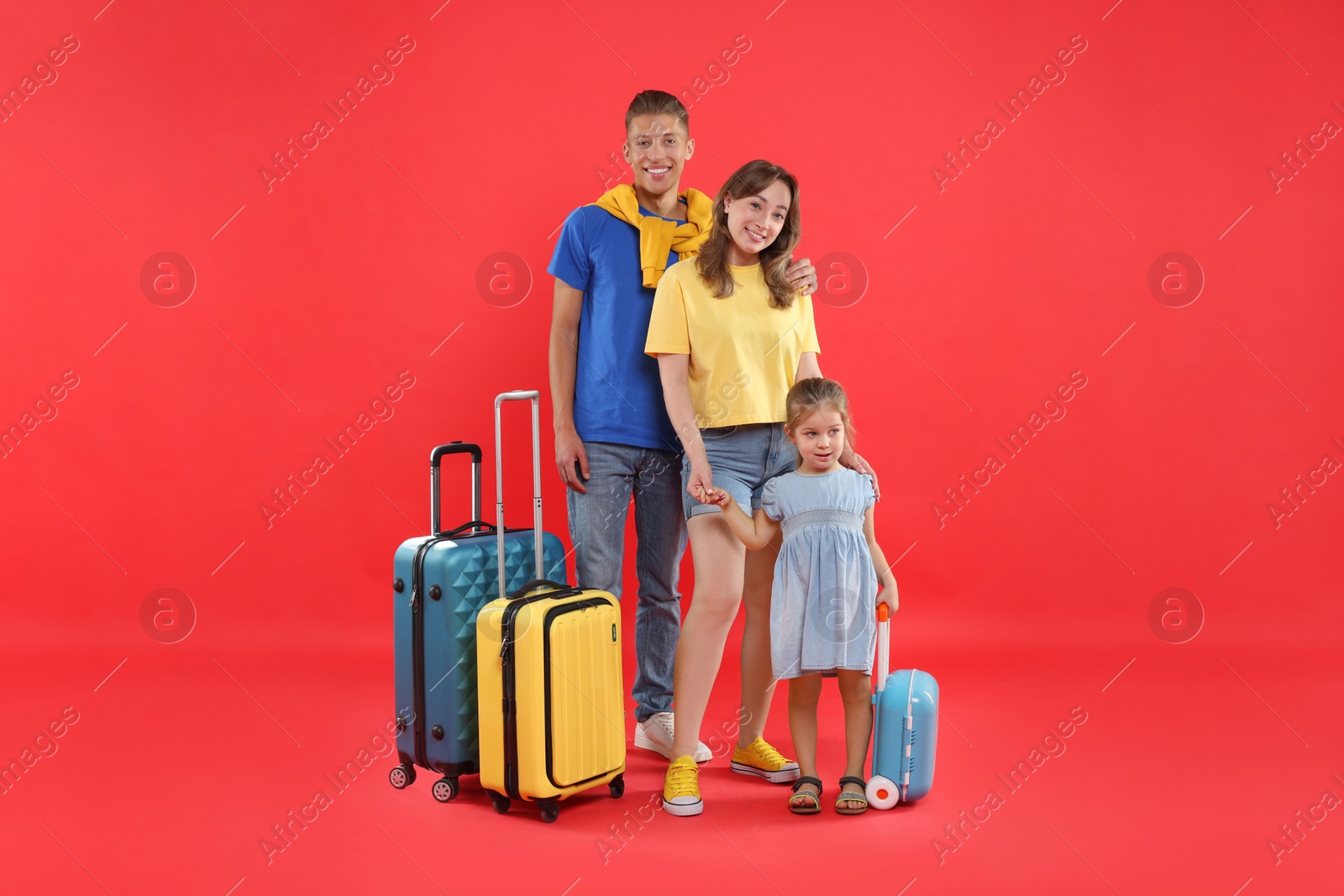 Photo of Travellers with suitcases and backpack. Happy family on red background