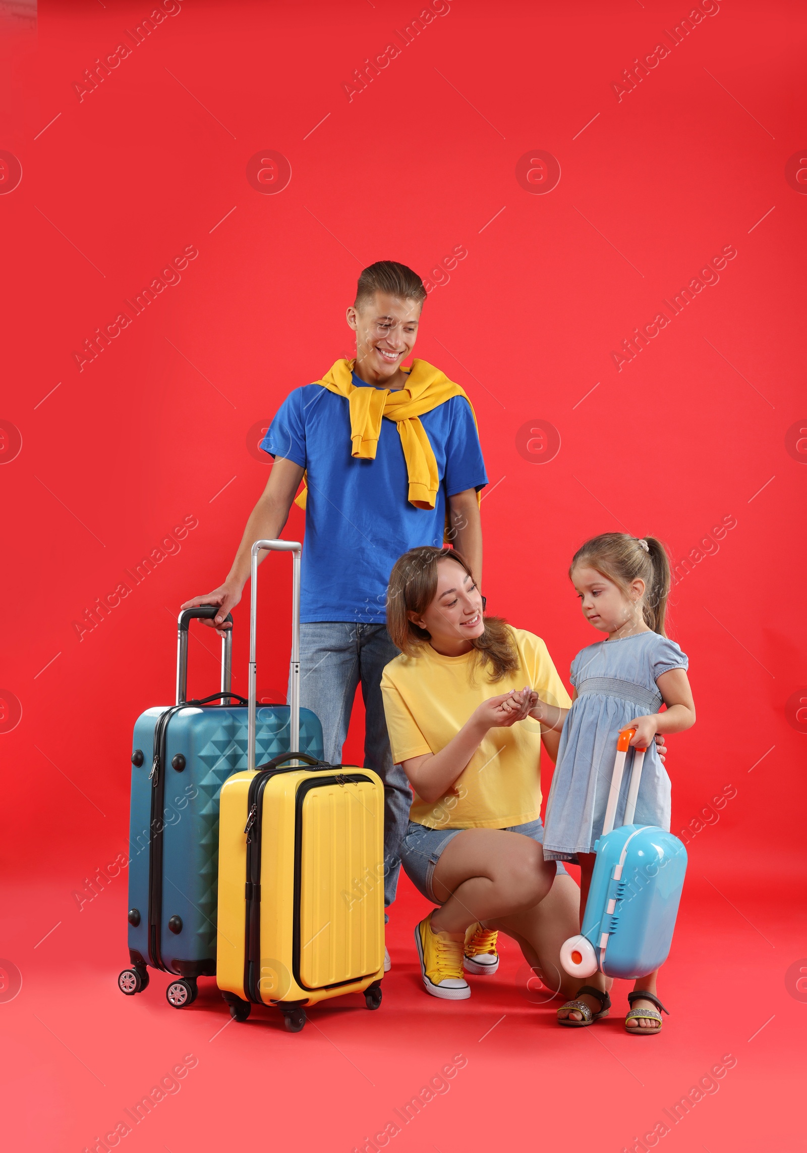 Photo of Travellers with suitcases. Happy family on red background