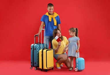 Photo of Travellers with suitcases, passport and tickets. Happy family on red background