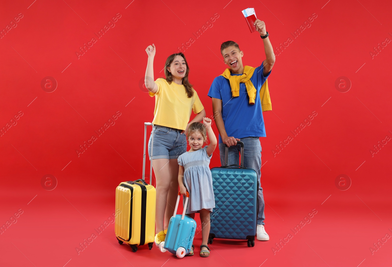 Photo of Travellers with suitcases, passport and tickets. Happy family on red background