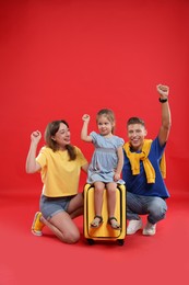 Photo of Travellers with suitcase. Happy family on red background