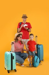 Photo of Travellers with suitcases and backpack. Happy family on yellow background