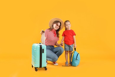 Photo of Travellers with suitcase and backpack. Young woman and cute little girl on yellow background