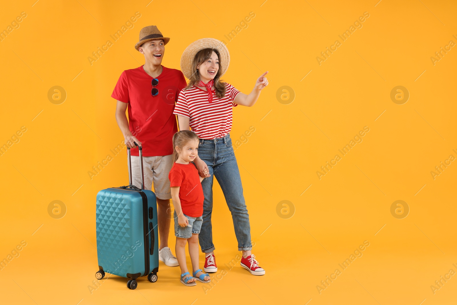 Photo of Travellers with suitcase. Happy family pointing at something on yellow background, space for text