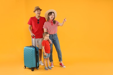 Photo of Travellers with suitcase. Happy family pointing at something on yellow background, space for text