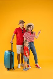 Photo of Travellers with suitcase. Happy family on yellow background