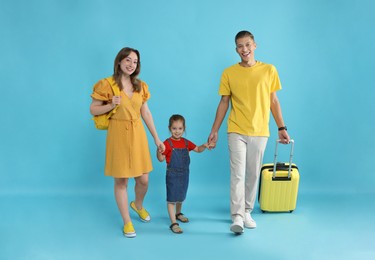 Photo of Travellers with suitcase and backpack. Happy family on light blue background