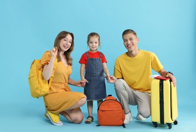 Photo of Travellers with suitcase and backpacks. Happy family on light blue background