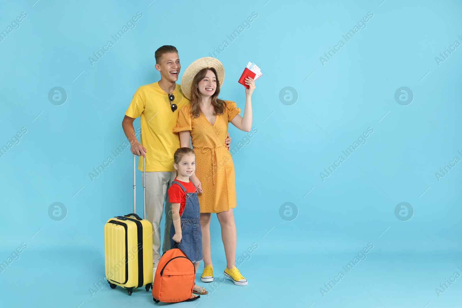 Photo of Travellers with suitcase, passport and tickets. Happy family on light blue background, space for text