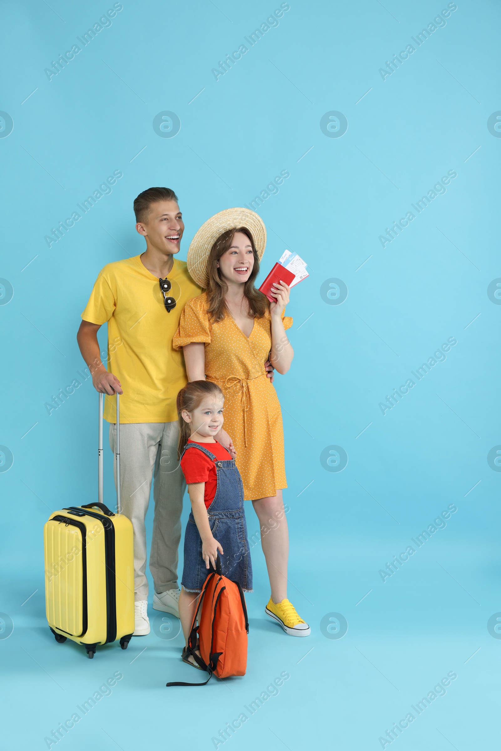 Photo of Travellers with suitcase, passport and tickets. Happy family on light blue background