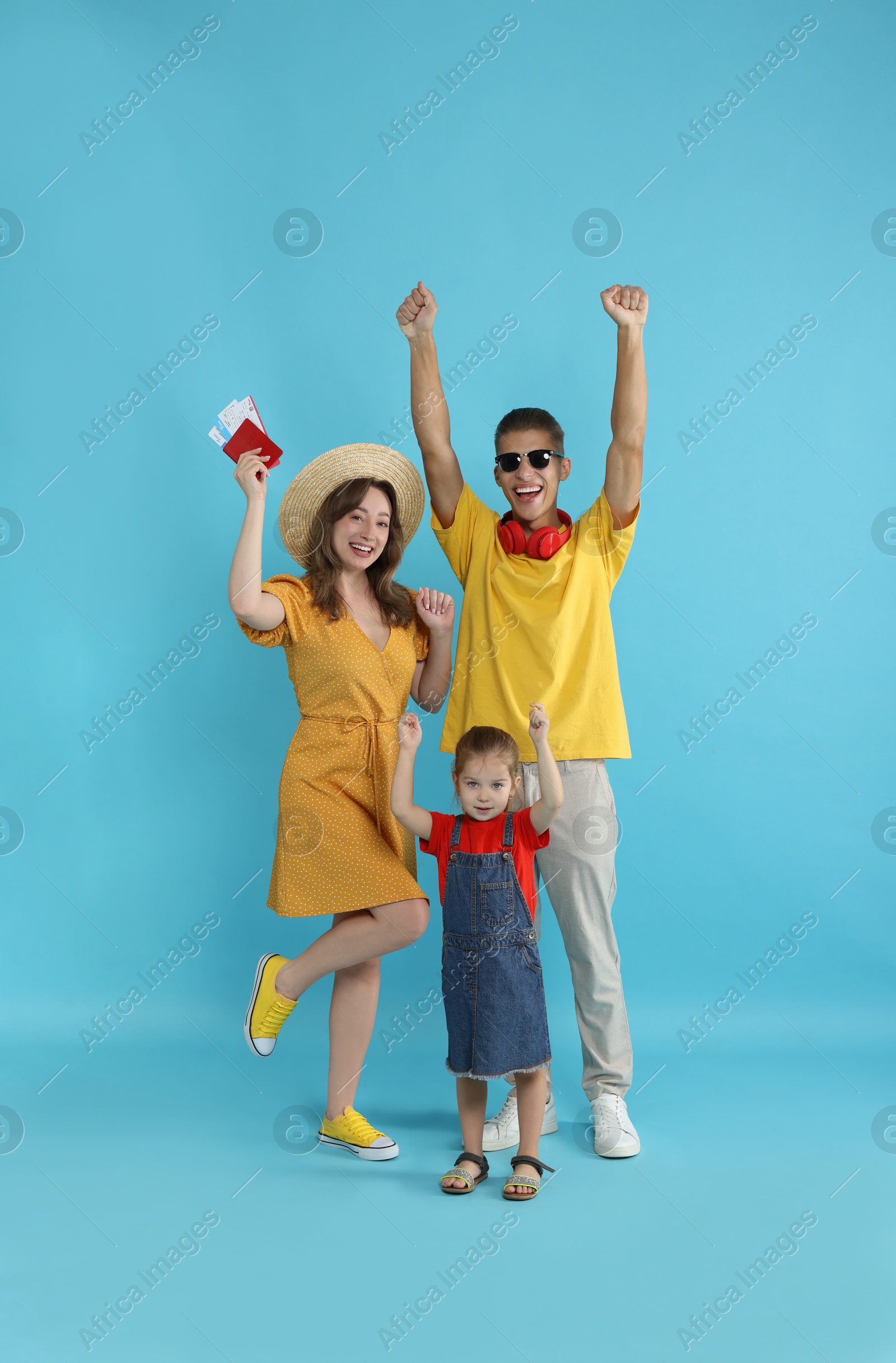 Photo of Travellers with passport and tickets. Happy family on light blue background