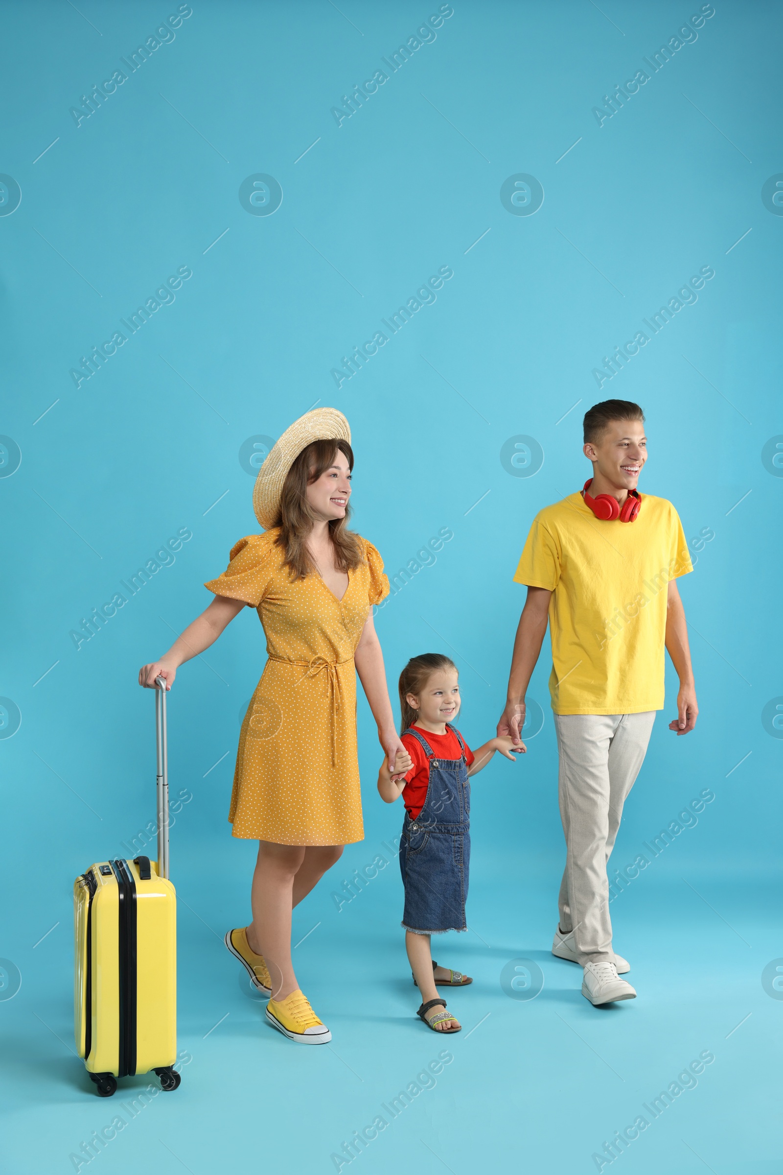 Photo of Travellers with suitcase. Happy family on light blue background