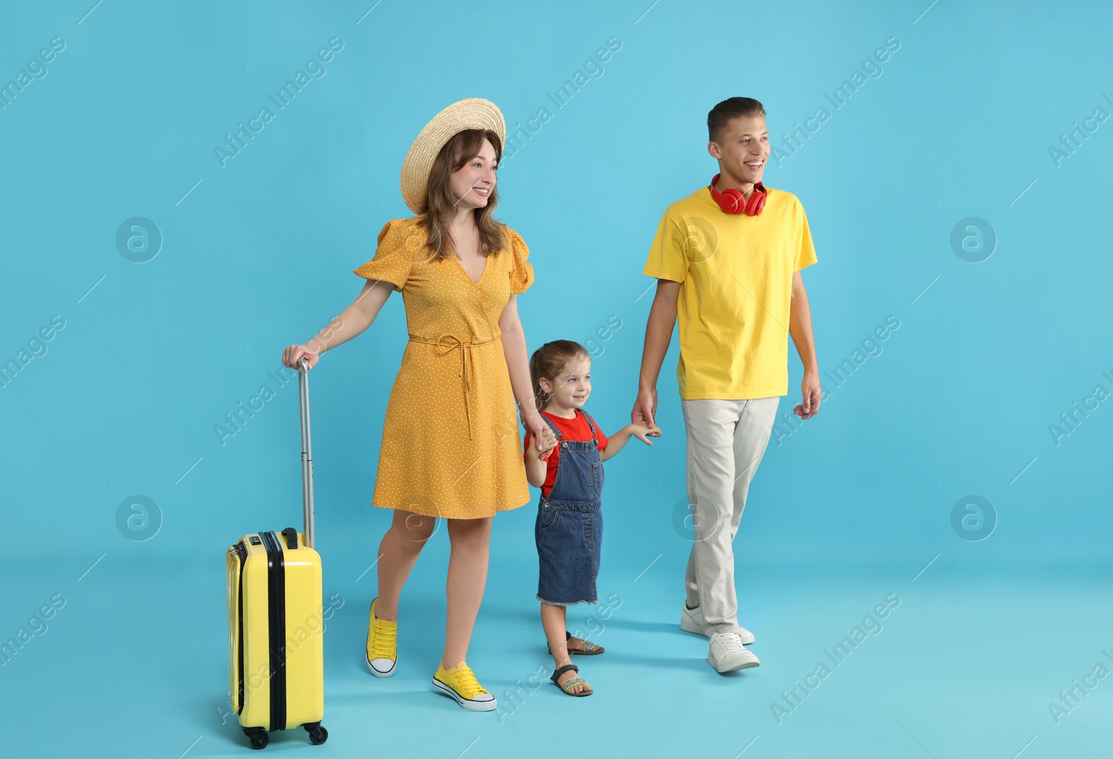 Photo of Travellers with suitcase. Happy family on light blue background