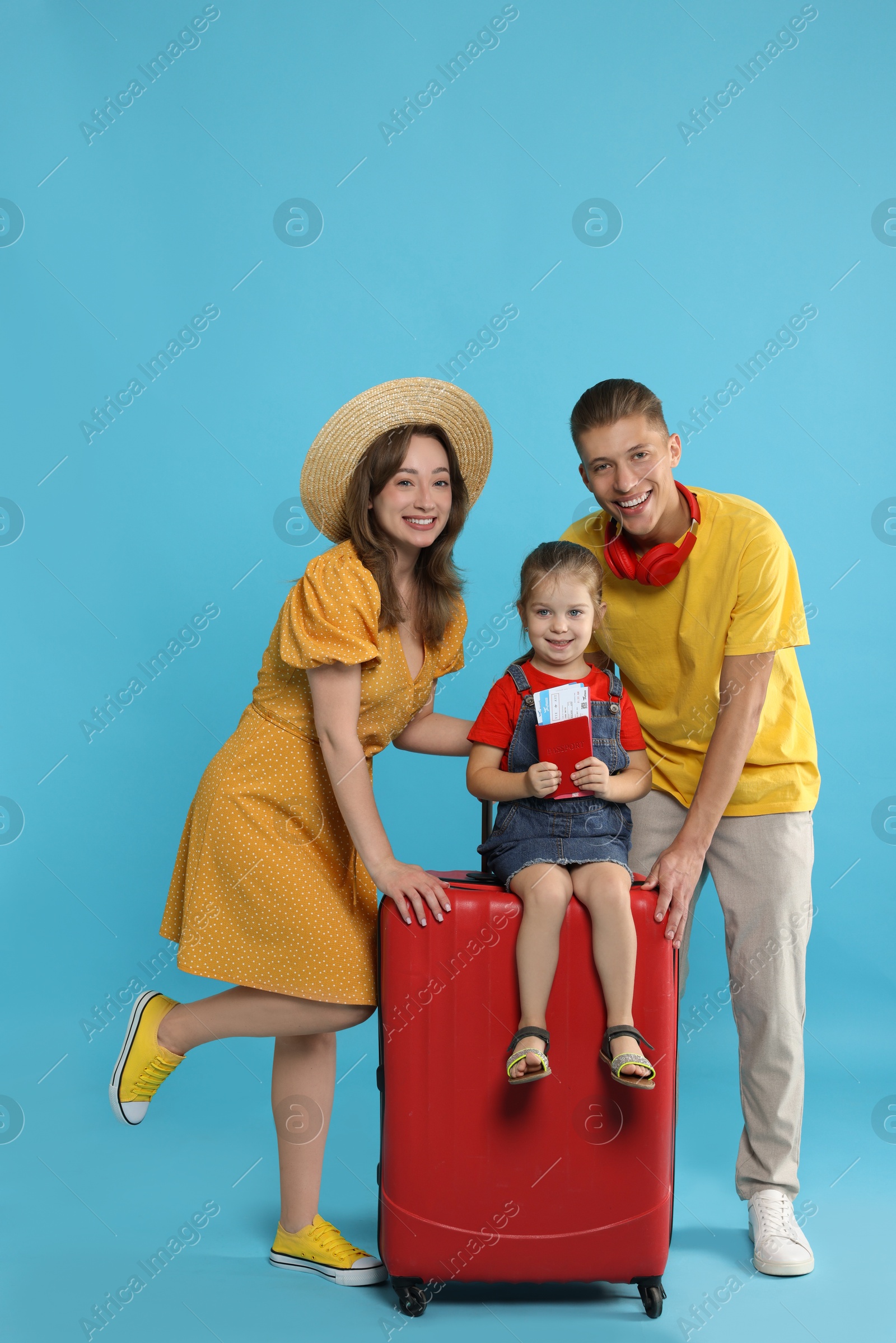 Photo of Travellers with suitcase, passport and tickets. Happy family on light blue background