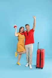 Photo of Happy travellers with suitcase on light blue background