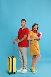 Photo of Happy travellers with suitcase on light blue background