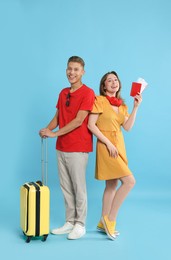 Photo of Happy travellers with suitcase on light blue background