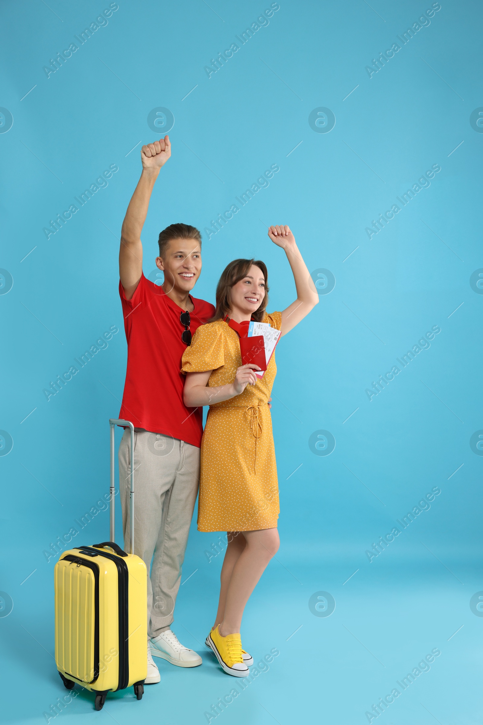 Photo of Happy travellers with suitcase on light blue background