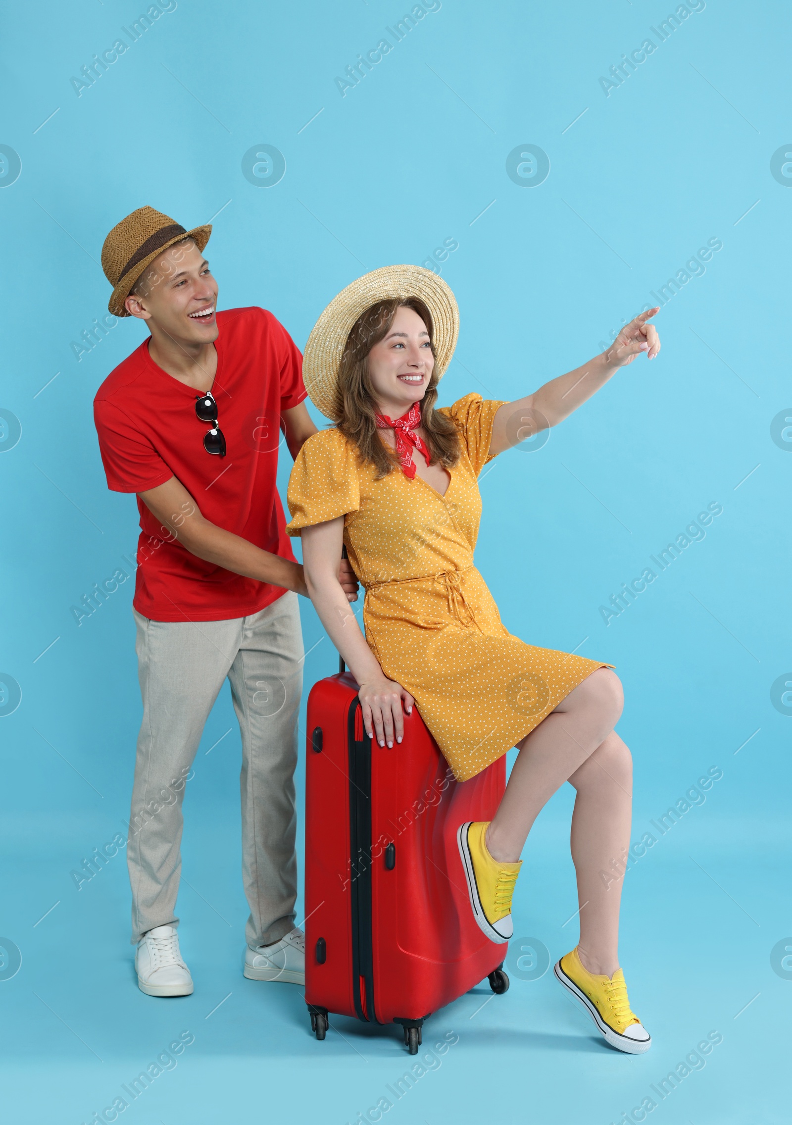 Photo of Happy travellers with suitcase looking at something on light blue background