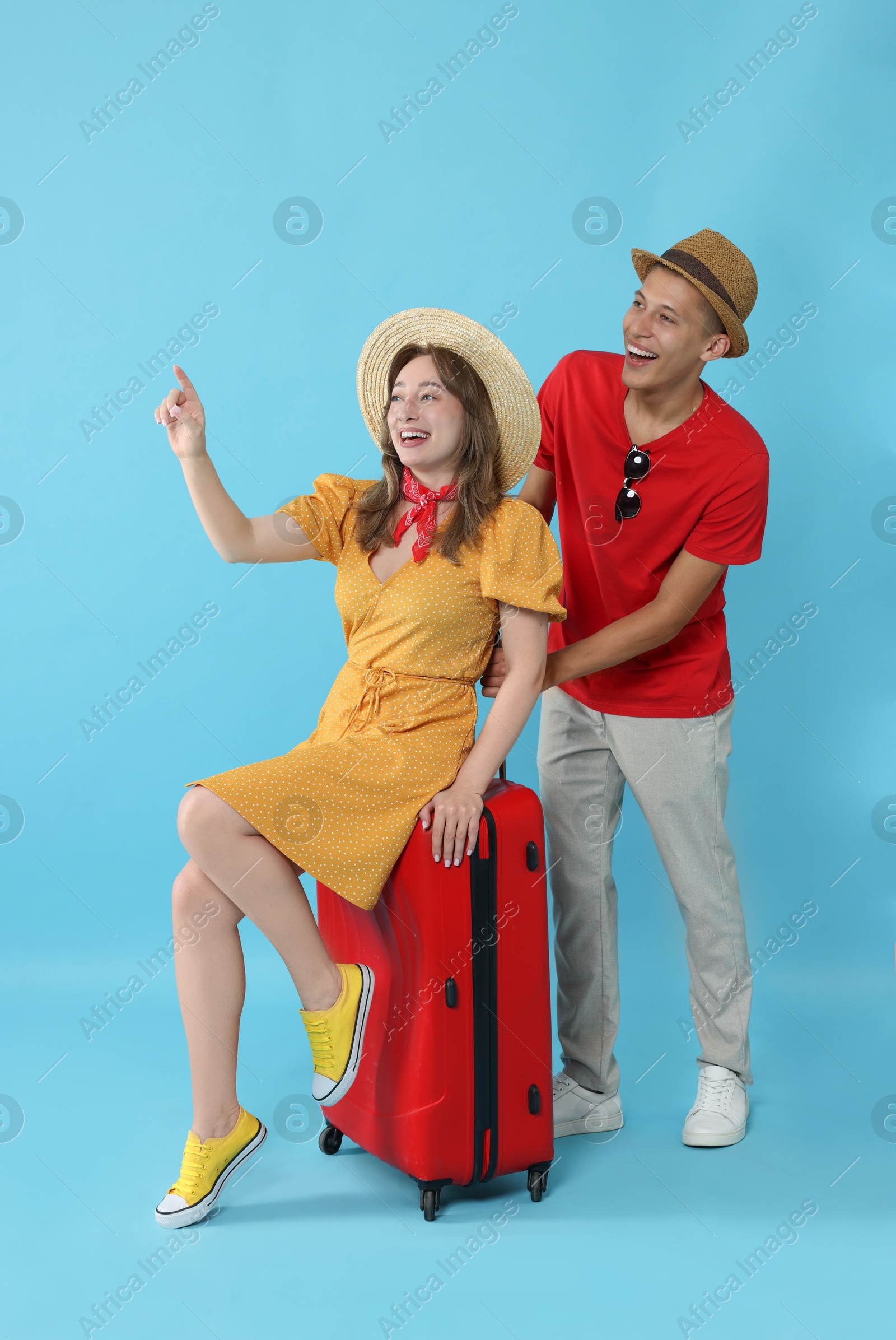 Photo of Happy travellers with suitcase looking at something on light blue background