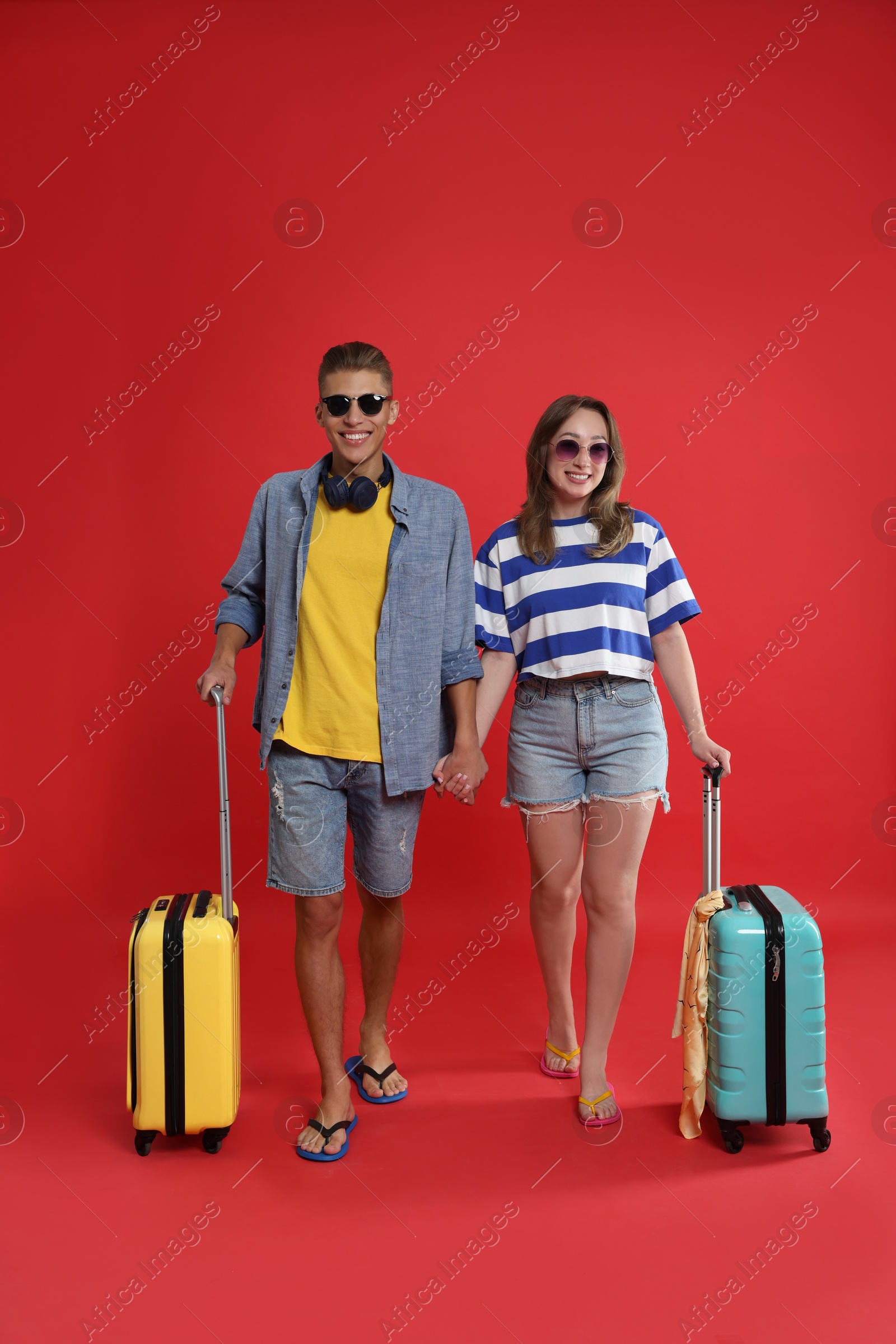 Photo of Happy travellers with suitcases on red background