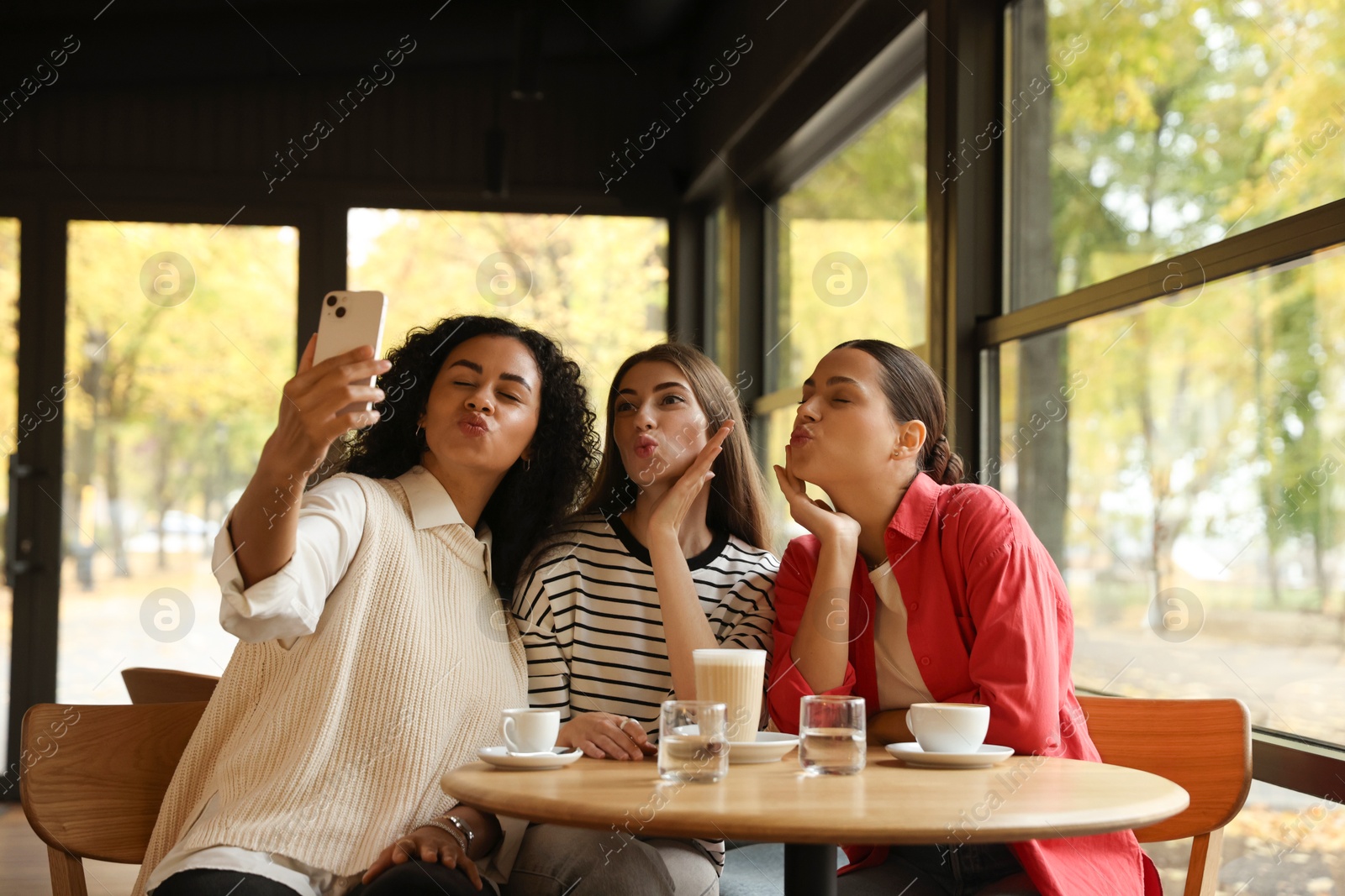 Photo of Happy friends taking selfie during coffee meeting in cafe