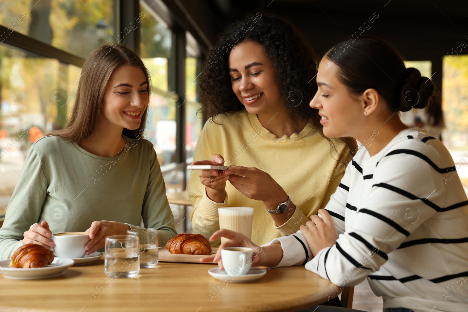 Photo of Woman taking picture of coffee drinks during meeting with her friends in cafe