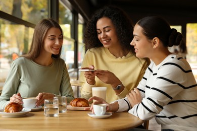 Photo of Woman taking picture of coffee drinks during meeting with her friends in cafe