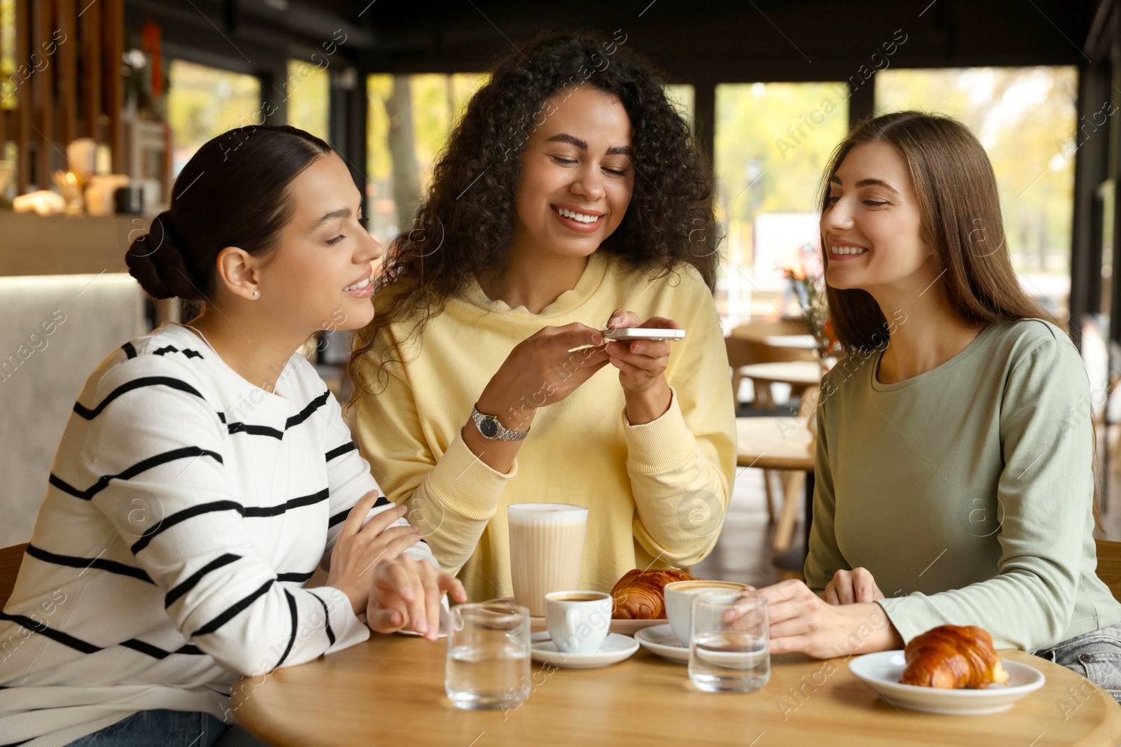 Photo of Woman taking picture of coffee drinks during meeting with her friends in cafe