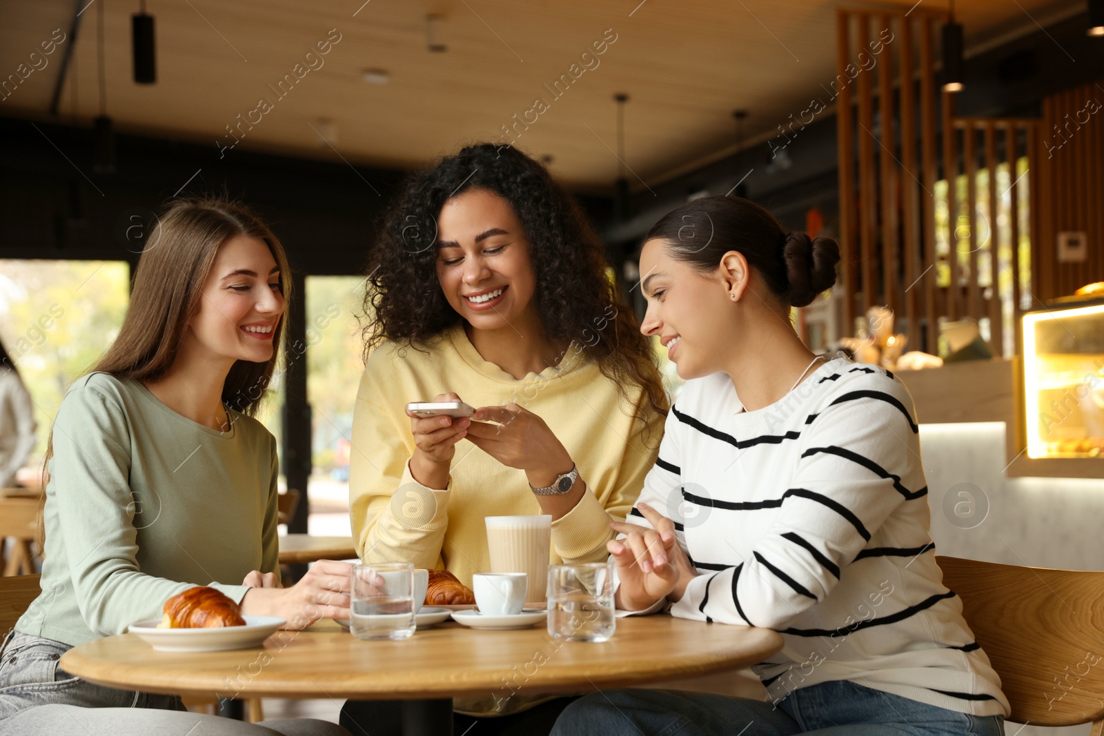 Photo of Woman taking picture of coffee drinks during meeting with her friends in cafe